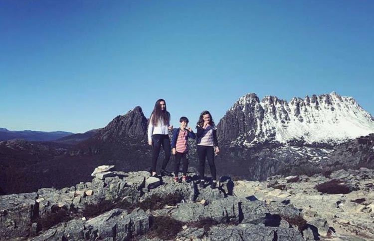 Families hiking with snowcapped Cradle Mountain in the back ground